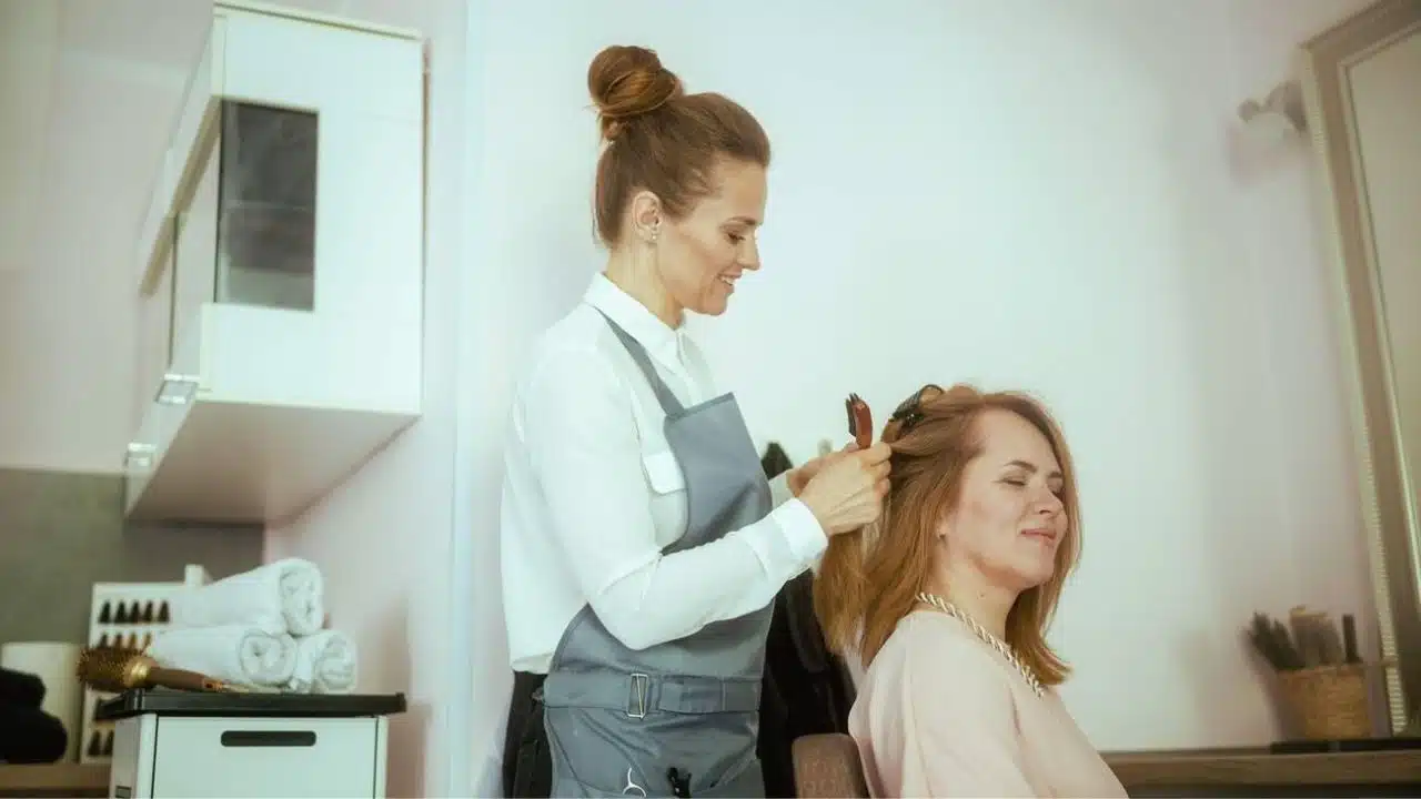 woman hairdresser in modern beauty salon with hairbrush and client.