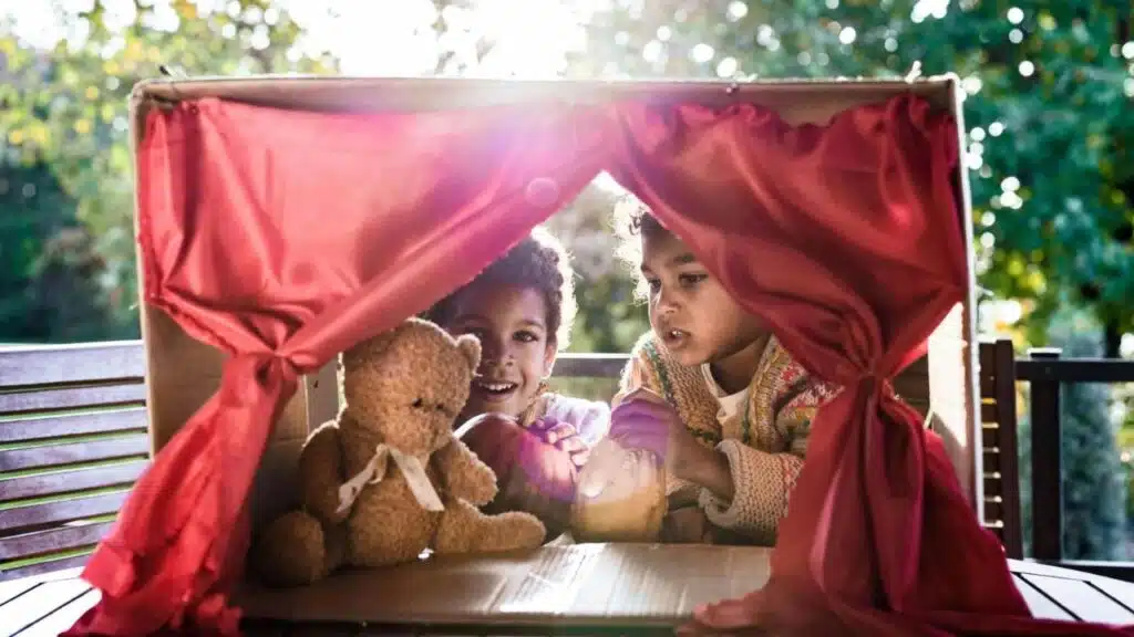 Happy black kids having a puppet show on a terrace