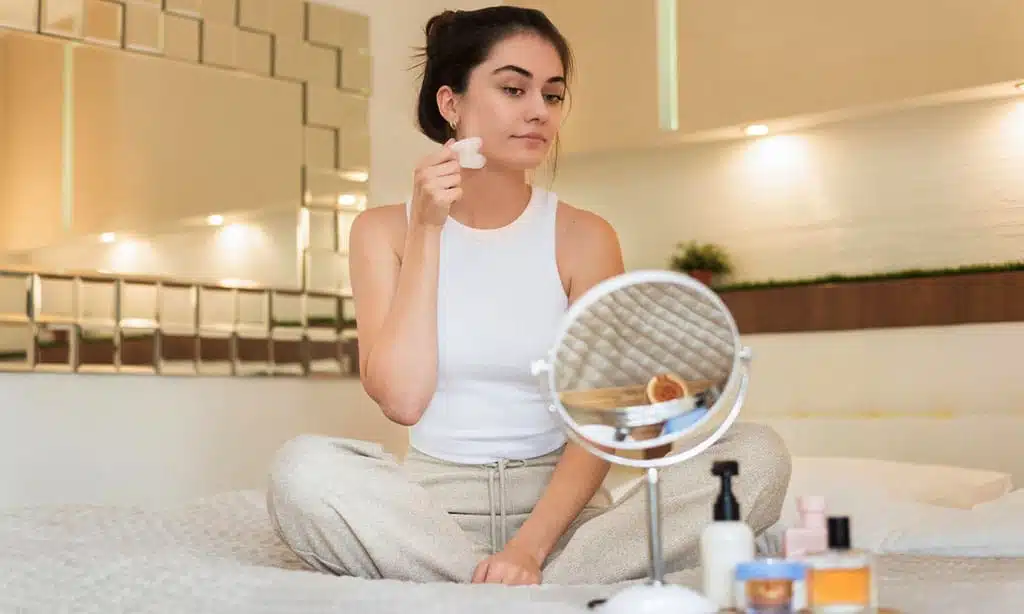 Young woman applying makeup in cozy bedroom