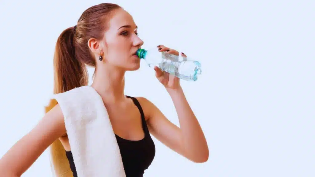 Woman after sport drinking water from bottle