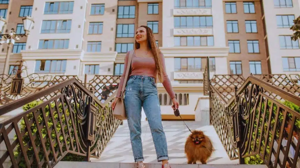 Smiling woman with dog moving down on steps in front of building