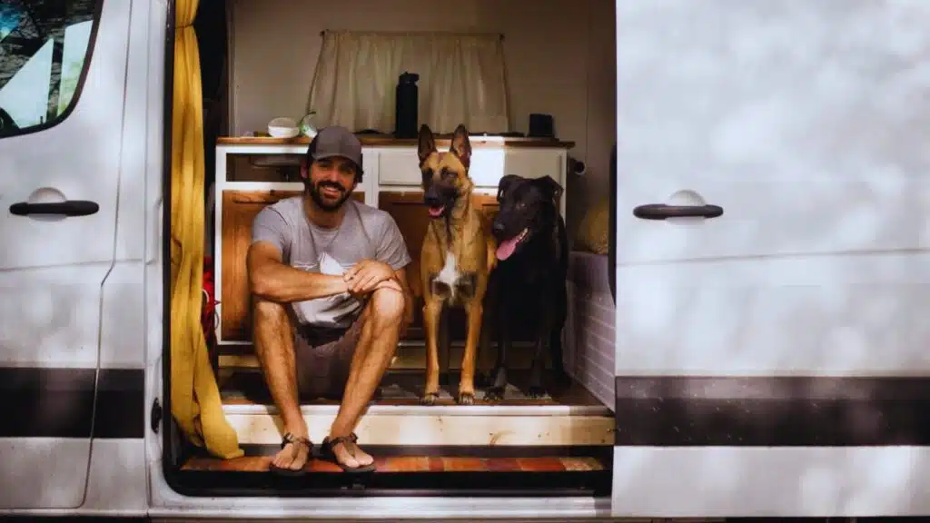 Portrait of smiling man sitting with dogs in motor home