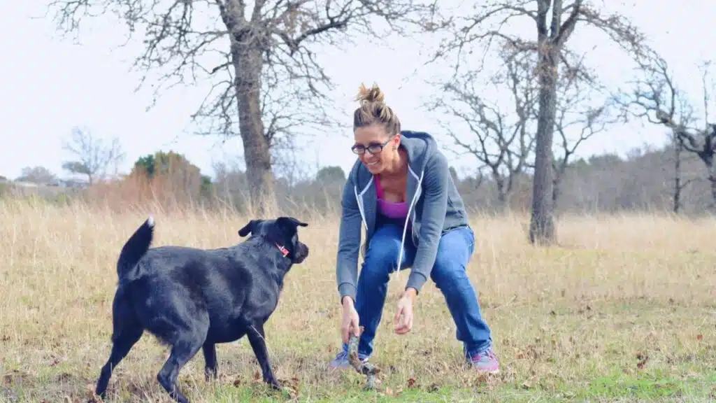 Woman playing fetch with pet dog in pasture