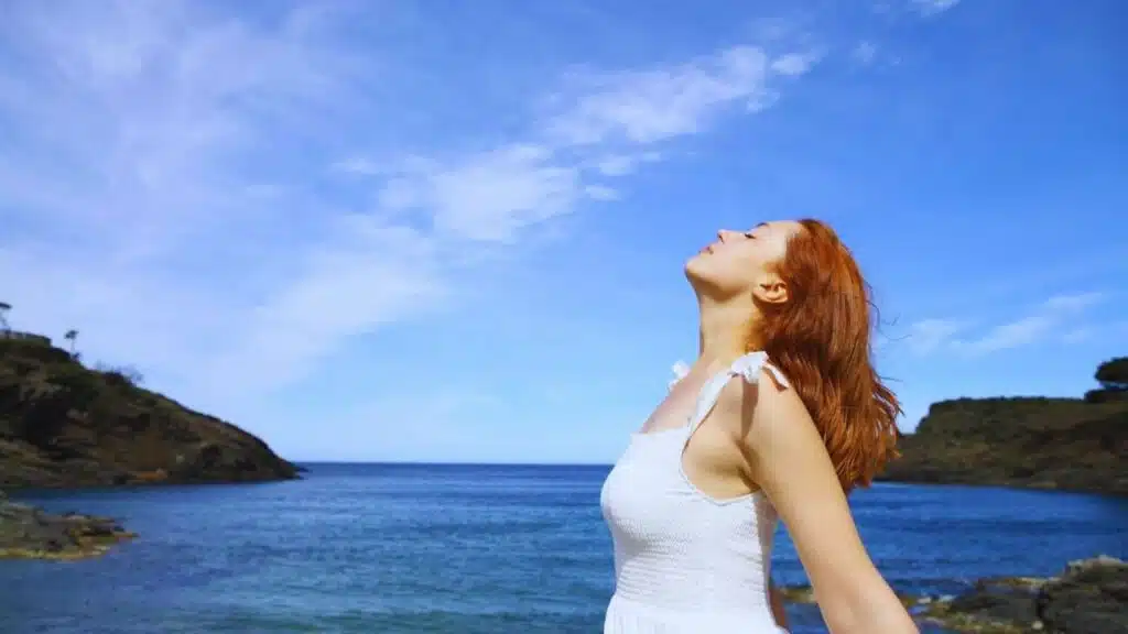 Profile of a relaxed lady in white dress breaths fresh air on the beach