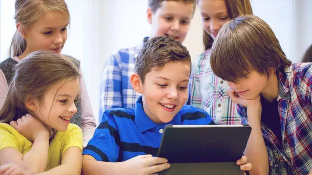 Group of children smiling and looking at a tablet together