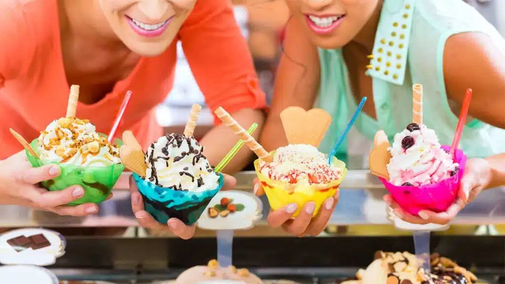 Two friends enjoying colorful bowls of ice cream with various toppings.