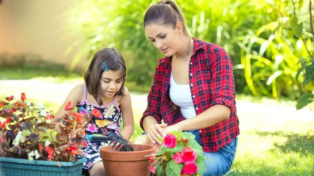 Woman and young girl planting flowers together in a garden