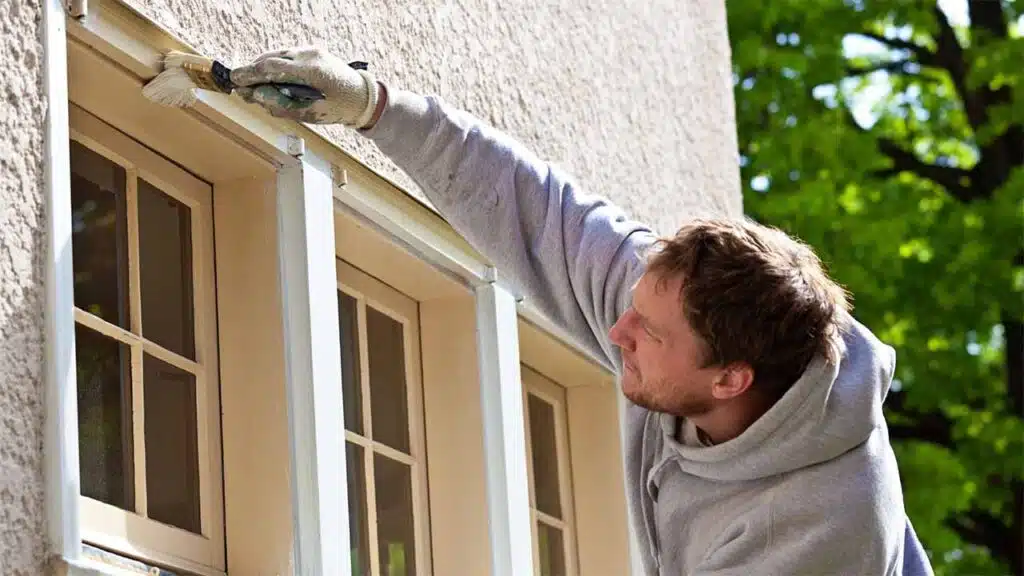 Person painting an exterior window frame