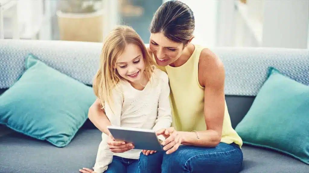 Mother and daughter smiling while looking at a tablet