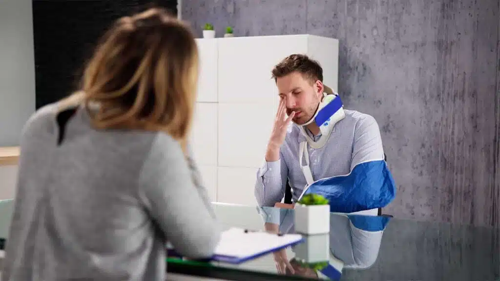 Injured man with a neck brace and arm sling consulting with a woman.