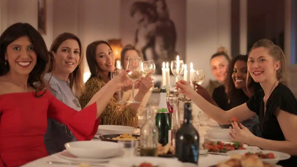 Group of women toasting with wine glasses at a candlelit dinner