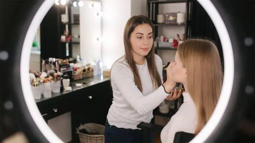 Makeup artist applying foundation to a client in a beauty studio.
