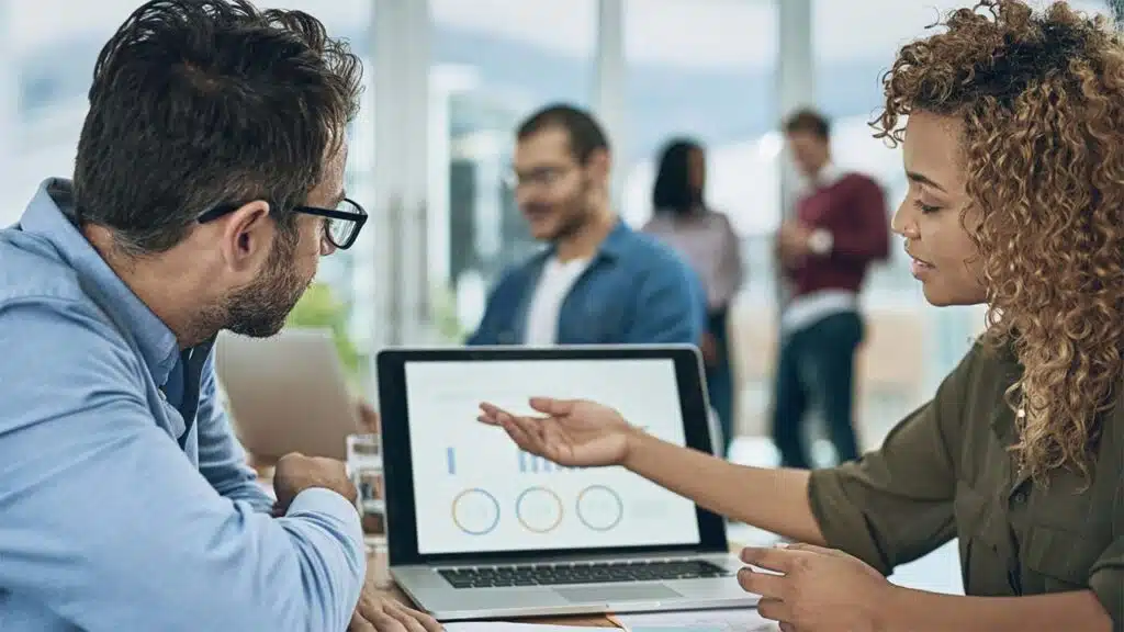 Colleagues collaborating on a project with data on a laptop screen