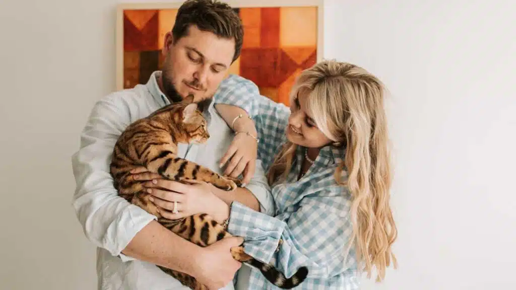 Couple bonding with their Bengal cat at home.