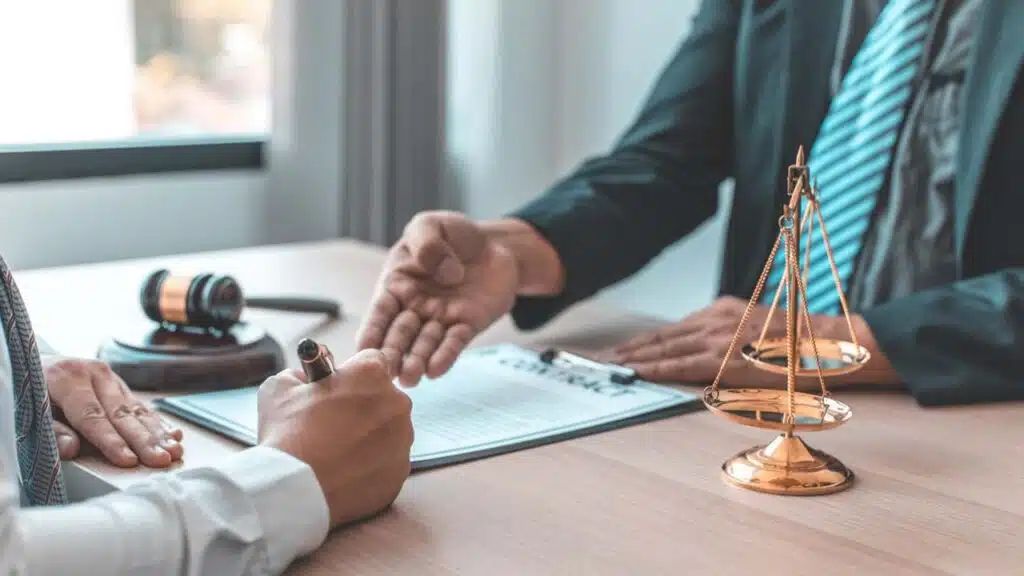 Close-up of a lawyer and a client discussing and signing a legal document at a desk