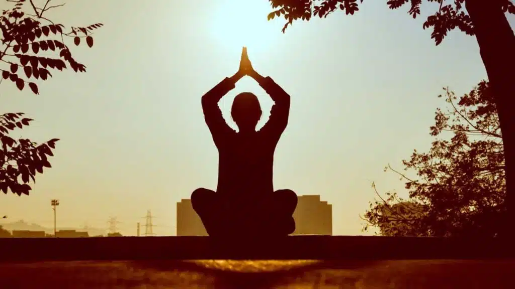 Silhouette of a person meditating at sunrise.