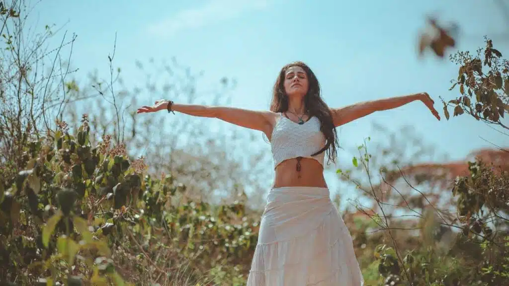 Woman embracing nature with open arms outdoors.