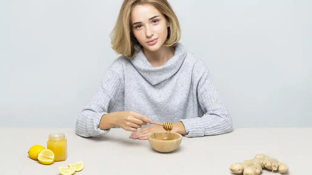 Woman preparing a mixture with honey, lemon, and ginger.