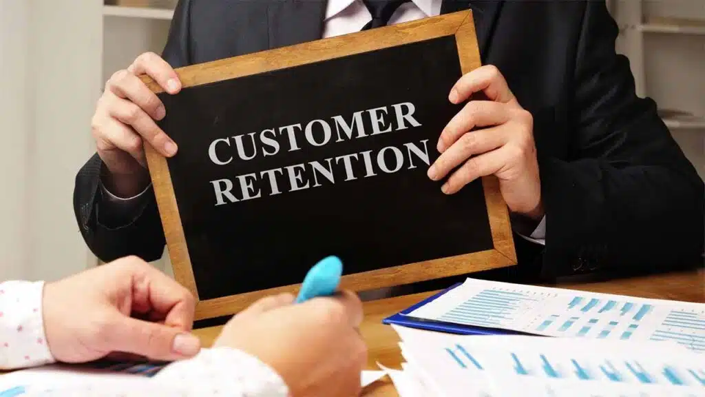 Person holding a "Customer Retention" sign at a desk