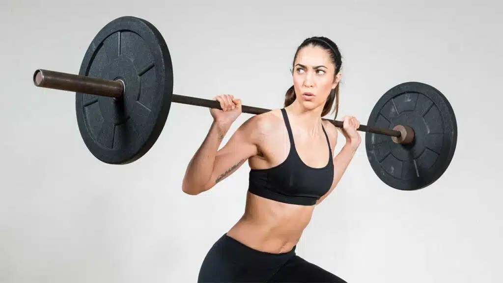Woman lifting heavy barbell in gym.