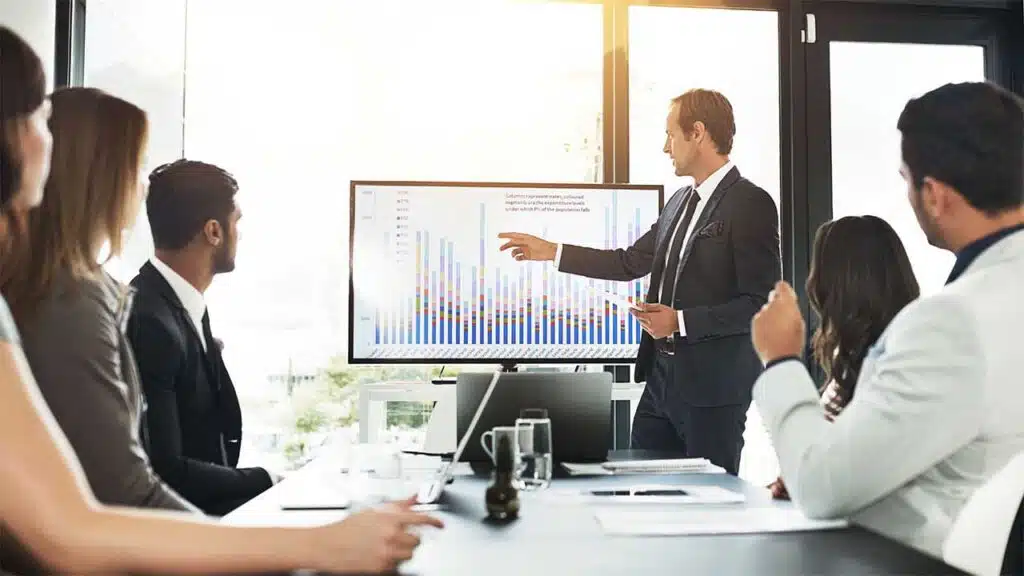Business presentation with a man explaining data on a screen to colleagues.