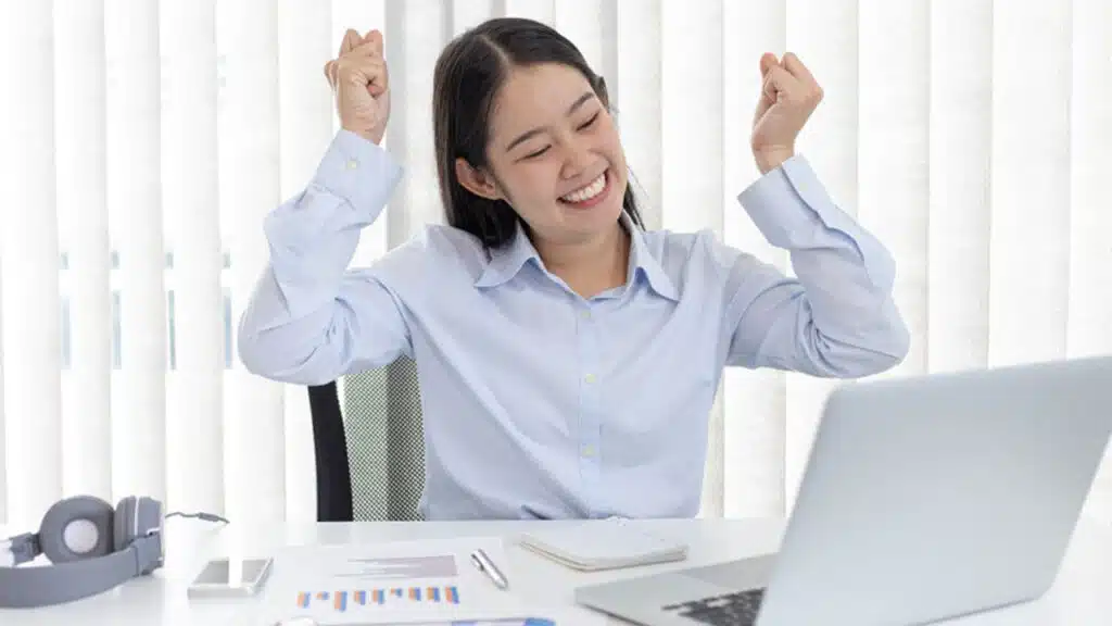 Happy woman celebrating a success at her desk
