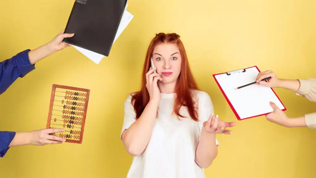 Overwhelmed woman multitasking with office tools.
