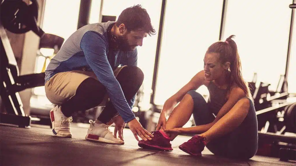 Trainer helping a woman with a foot injury at the gym.