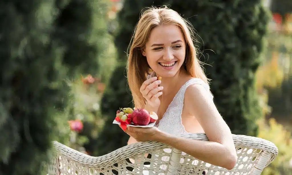Woman enjoying fresh fruit outdoors.
