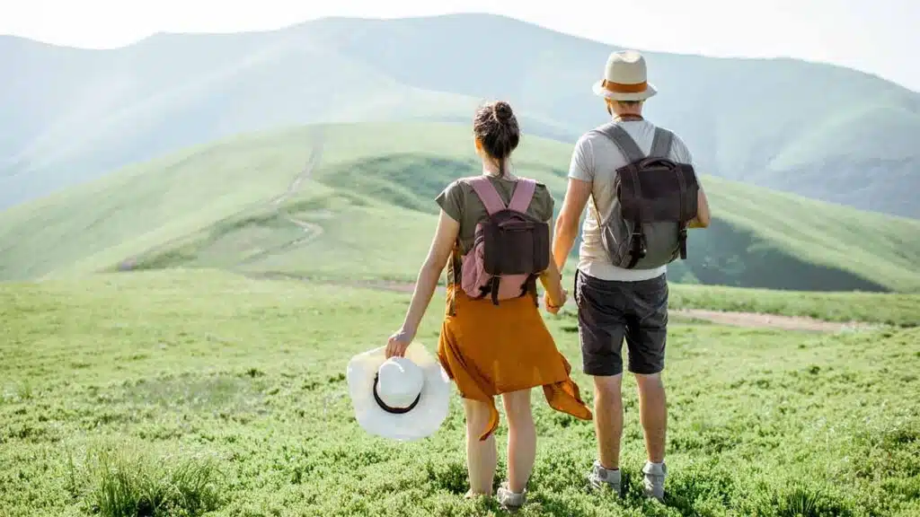 Couple hiking in lush green mountains.