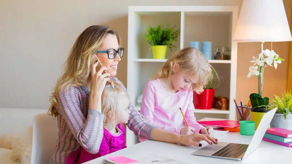 Multitasking mom working on laptop while managing kids at home