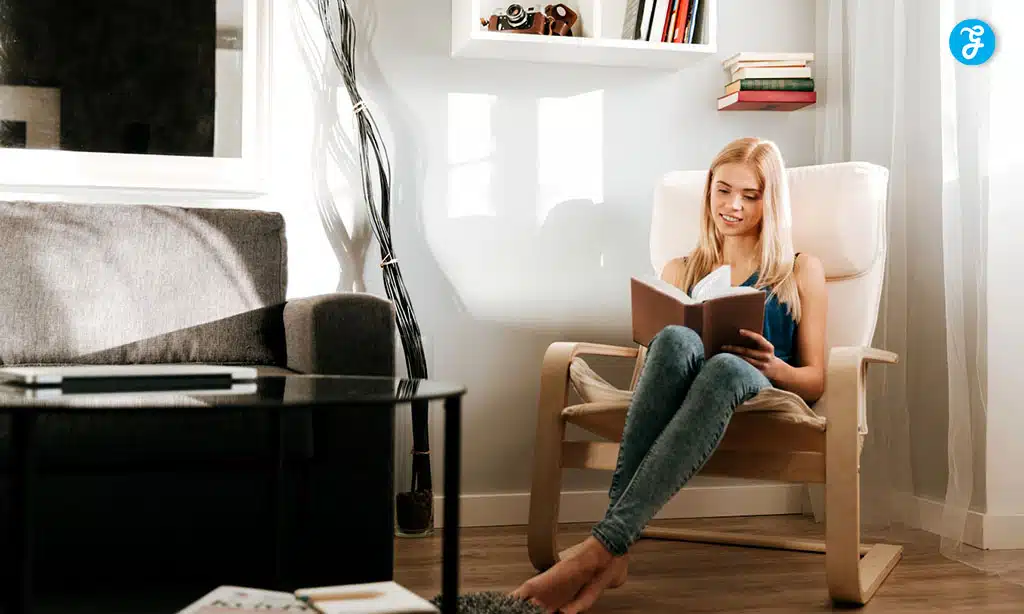 Young woman reading a book in a cozy living room chair