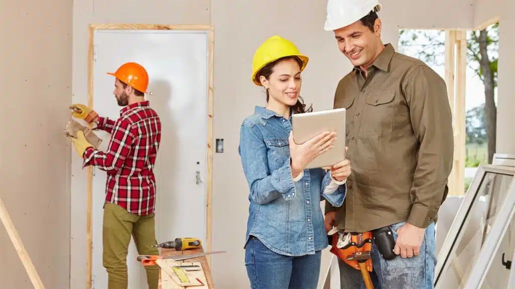 Construction team reviewing building plans on a tablet at a home renovation site