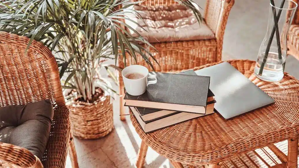 Cozy Wicker Furniture Setting with Coffee, Books, and Laptop