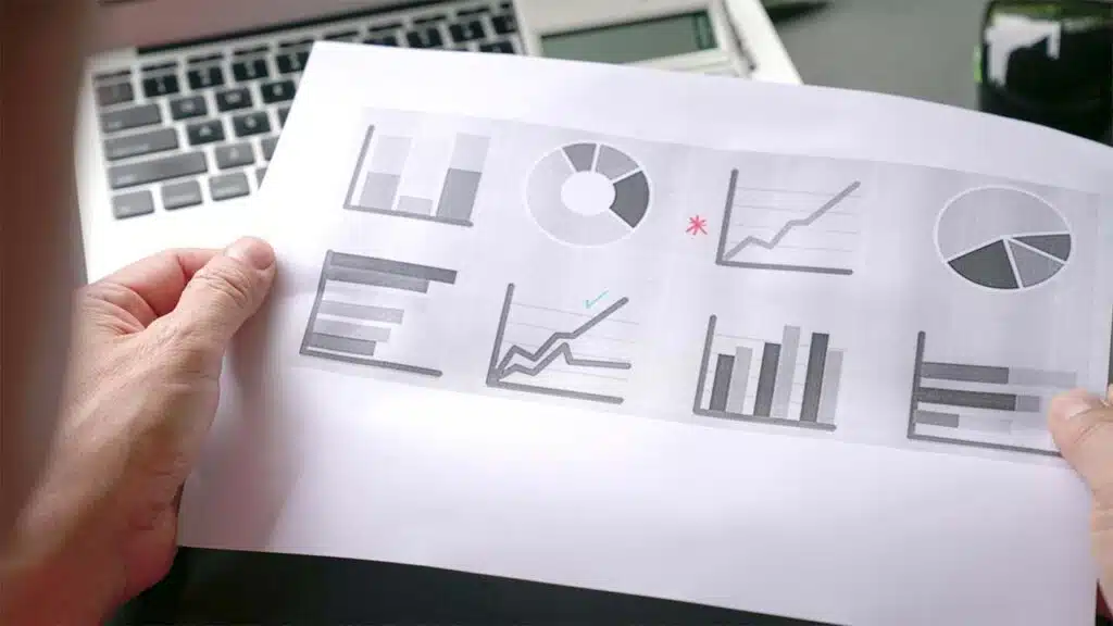 Business analytics concept showing a person reviewing printed charts and graphs