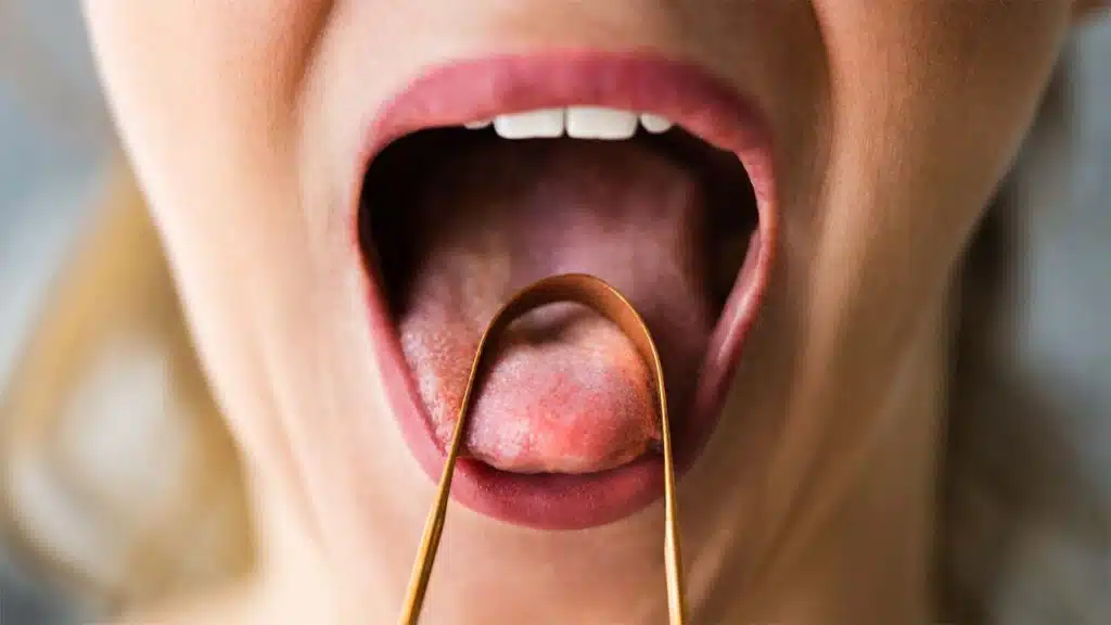 A close-up of a person using a tongue scraper for oral hygiene