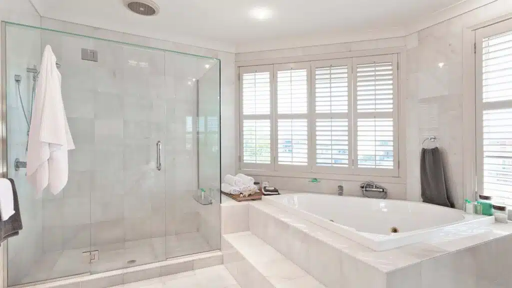Bright bathroom features a large walk-in glass shower, a spacious sunken bathtub