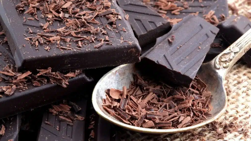 Dark chocolate bars stacked together, with chocolate shavings scattered on top