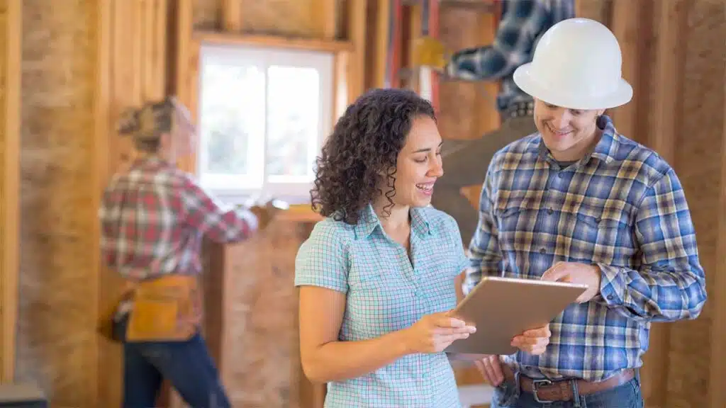 Worker is visible in the background, preparing a window frame