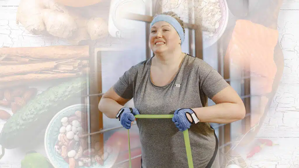 A smiling woman exercises with resistance bands, surrounded by healthy fat-burning foods.