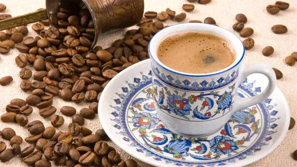 Traditional Turkish coffee in an ornate cup surrounded by roasted coffee beans