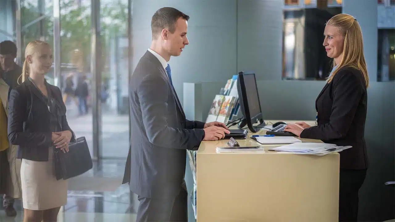 A man asking a question to a receptionist at a desk