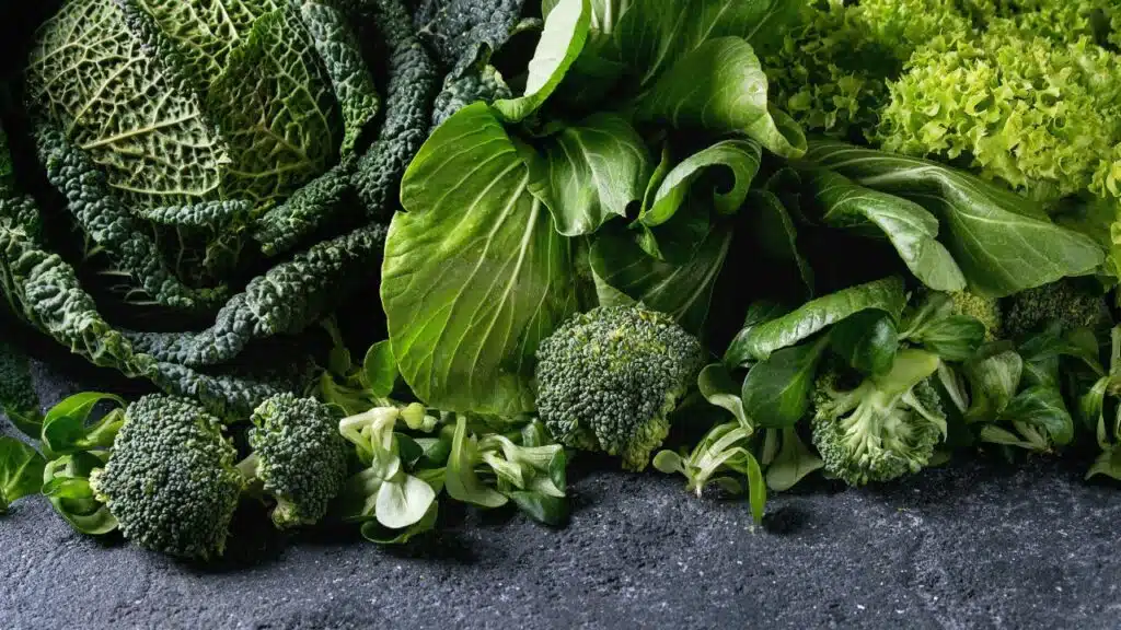 An assortment of fresh green vegetables, including broccoli, lettuce, cabbage, and other leafy greens