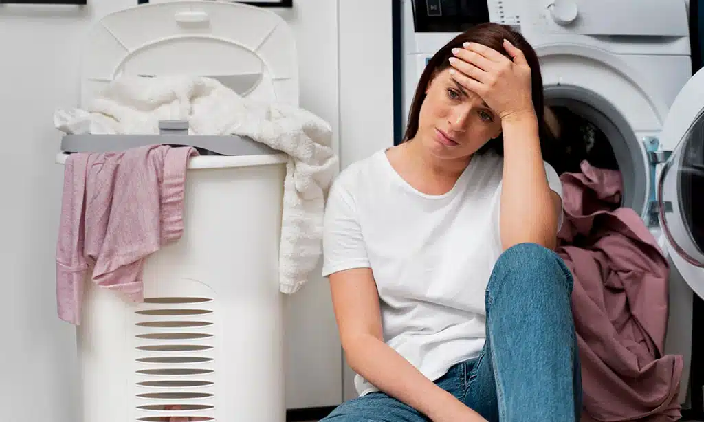 Overwhelmed woman sitting on the laundry room floor