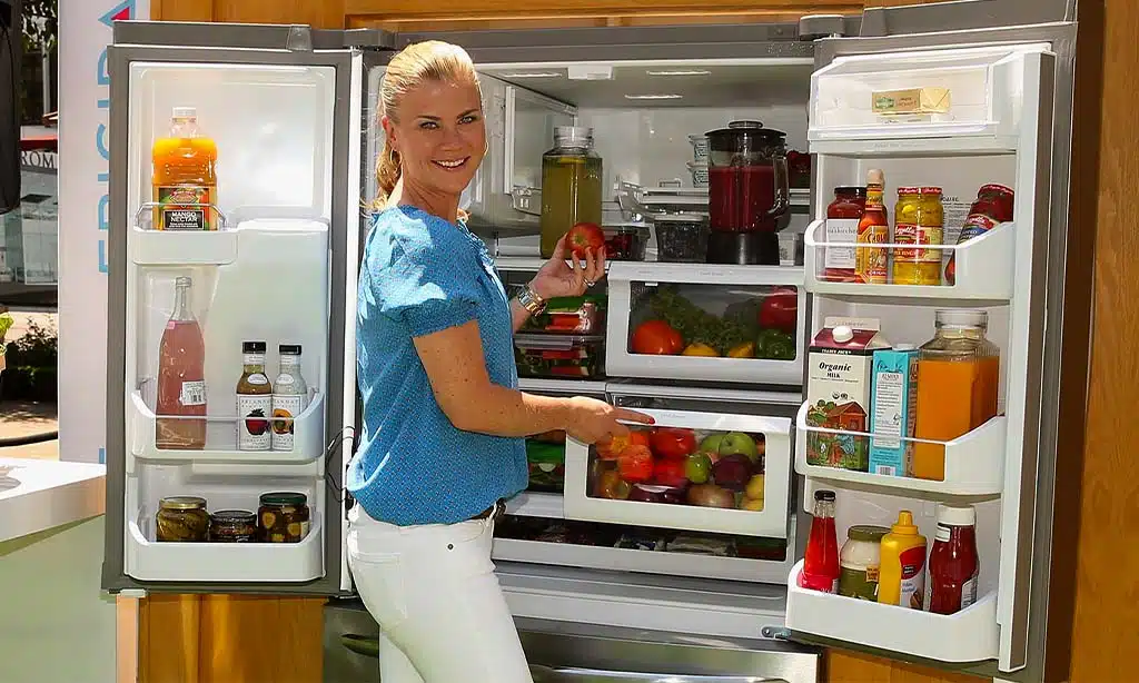 A woman stands in front of an open refrigerator
