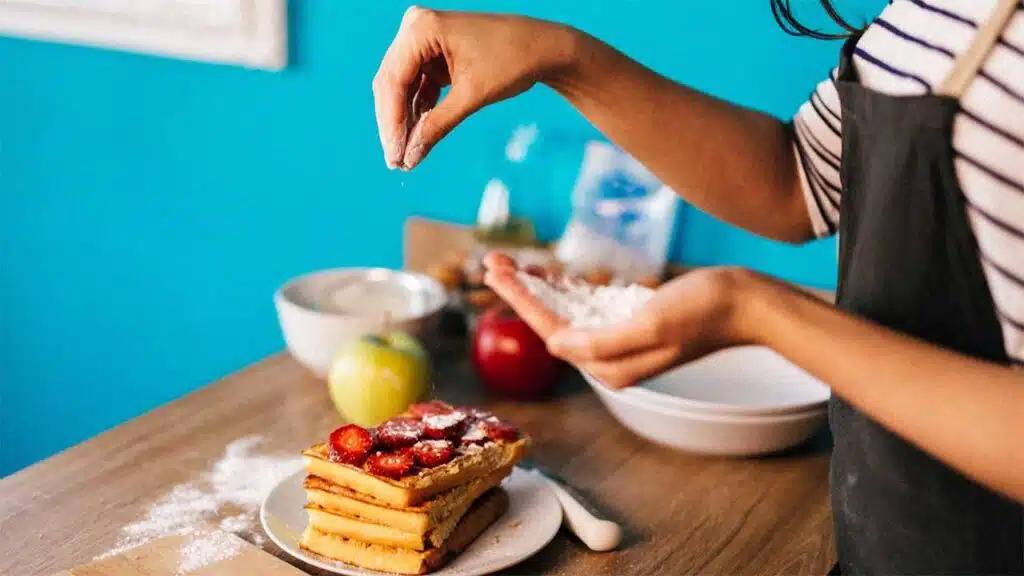Making delicious homemade waffles topped with fresh strawberries and a sprinkle of powdered sugar