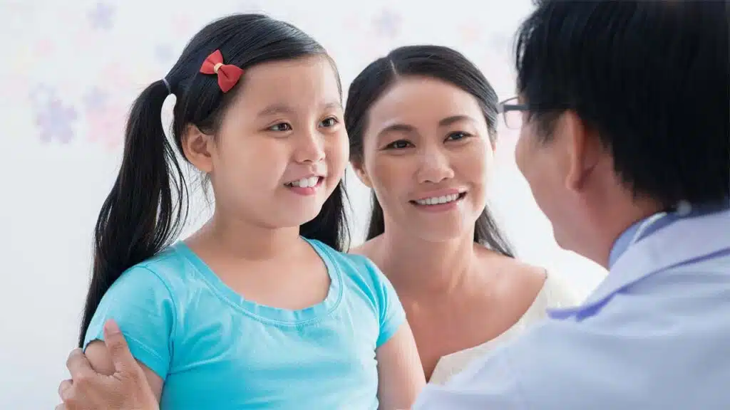 Happy moment between a young girl, her mother, and a doctor during a medical visit.