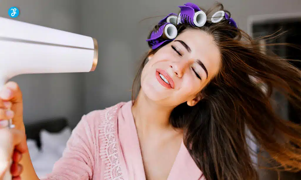 A joyful woman drying her hair with a white hairdryer