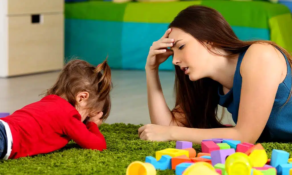 She is interacting with a small child who is lying on the floor as well