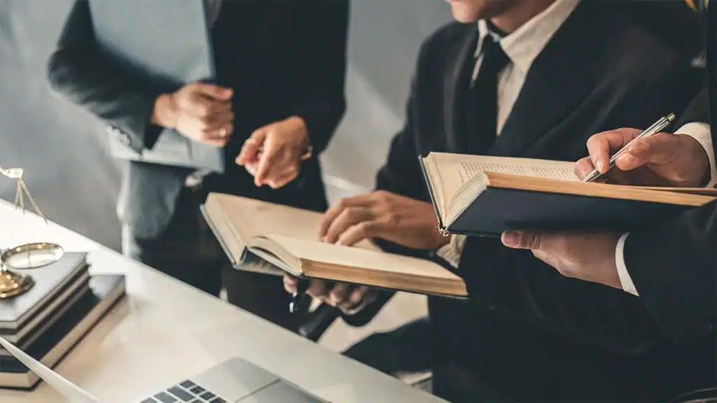 Group of lawyers in suits reviewing legal documents and books at a desk
